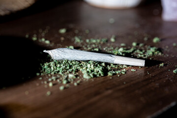 Flat lay marijuana joint rolled over scattered cannabis