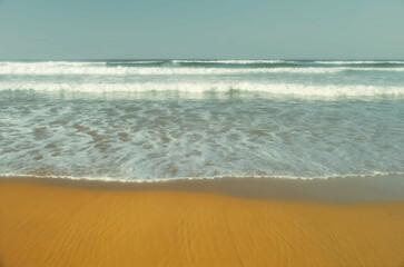 Fototapeta na wymiar Whitewater waves rolling onto a sandy shore