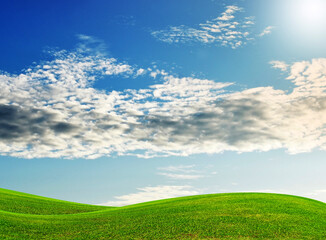 green field and blue sky with clouds