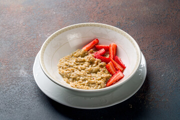 Oatmeal with strawberry on bowl on dark stone table