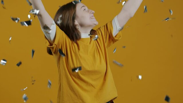 Slow motion portrait of pretty girl feeling sad and lonely then seeing confetti faling down and laughing dancing jumping enjoying party