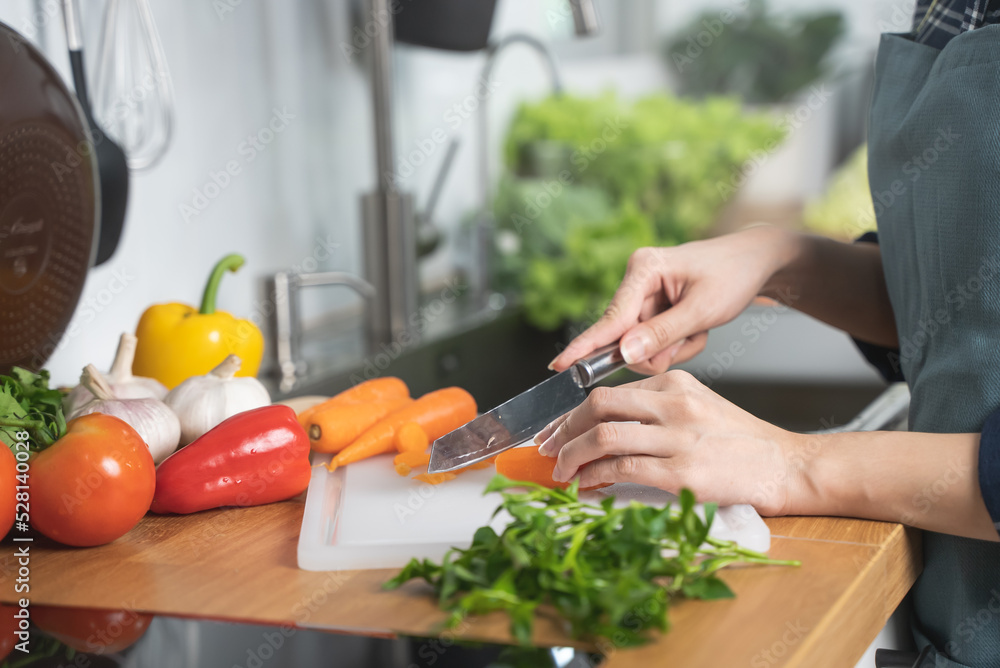 Wall mural Asian housewife woman slice carrot to preparing salad ingredients for dinner meal  in the kitchen