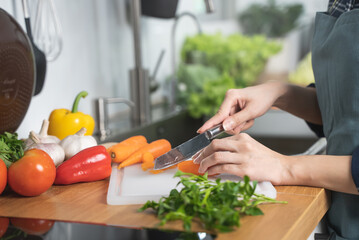 Asian housewife woman slice carrot to preparing salad ingredients for dinner meal  in the kitchen