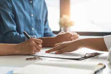 financial investor advisory.  Close up hand pointing at contract and document while sitting together with young couple at the desk in office