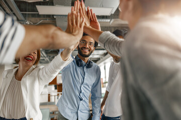 Happy group of multi ethnic coworkers stacked hands together as concept of corporate unity