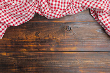 Checkered red and white tablecloth on an old wooden brown background with copy space. Flat lay, top view. Background of menu for the restaurant, copy space. Fabric red and white cover on the table.