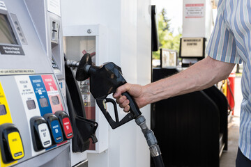 Refuel cars at the pump station. Man filling up his vehicle at the gas station holding pump nozzle 