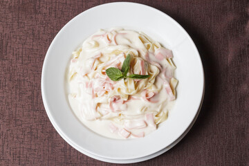 Creamy Fettuccine. Pasta with ham and parmesan on a white ceramic plate with Italian food - Imagen