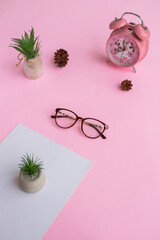 Cat's eye glasses in the photo from above with a minimalist concept on a purple paper background with an alarm clock decoration and dry leaves
