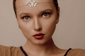 Girl with Dubai make-up. Perfect arrows, red lips, gold jewelry, jewelry on the forehead. Indian...