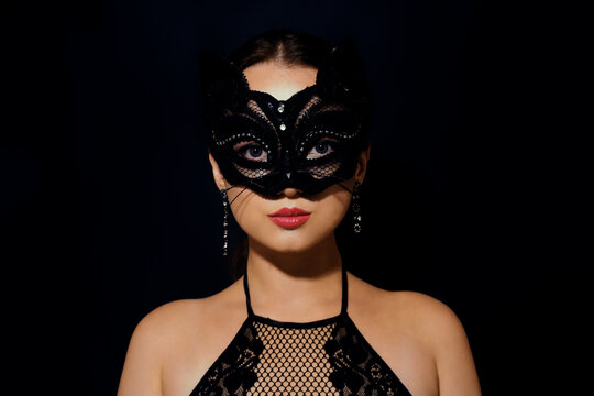 The girl in the mask. Masquerade, halloween. Girl in a cat mask. Catwoman on a beautiful background in a beautiful lace top with long earrings .