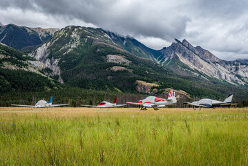 Four airplanes tied down at the Jasper Airstrip near Jasper, Alberta with mountains in the background