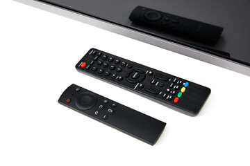 Close-up of a television with two remote controls isolated on white background. Upside view.