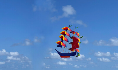 flying ship, rainbow colored ship kite flies on the blue sky and cloud