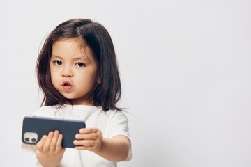 Fototapeta premium close horizontal portrait of a little happy girl with a fashionable smartphone in her hands