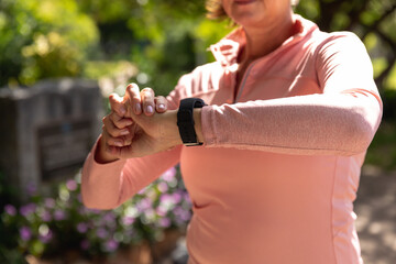Naklejka premium Female jogger using smart watch in the park