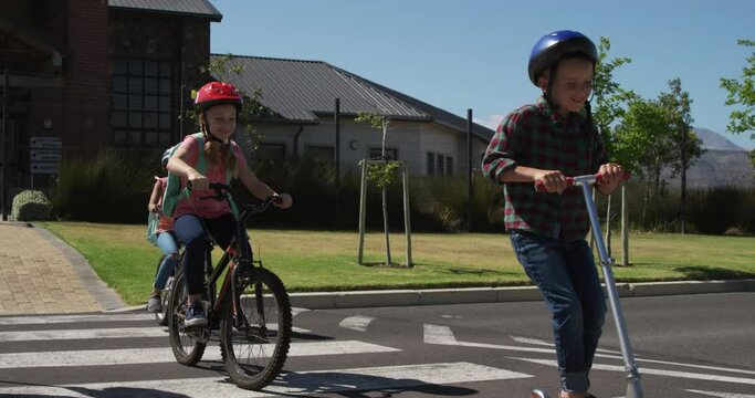 Group of kids riding bicycles and scooter and crossing the road