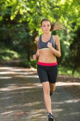 Fototapeta premium young woman jogging on footpath in park
