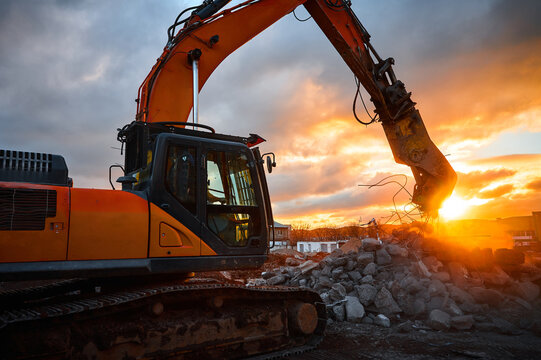 Powerful crusher destroys armored cement leftovers at sunset
