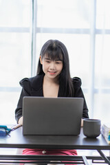 Asian business woman working in accounting Finance with laptop and graph paper in the office, vertical image.