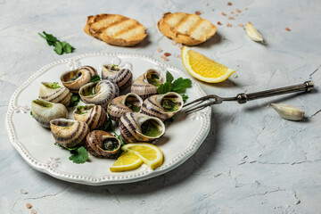 Escargots de Bourgogne Snails with herbs, butter, garlic, glass of white wine on a light background, gourmet food. Restaurant menu, Traditional French cuisine