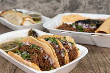 Mexican food feast on the table with choices of burrito, birria stew meat combo, or 3 tacos served...