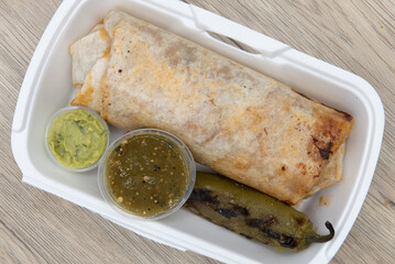 Overhead view of loaded mexican cuisine burrito, bulging at the flour tortilla and served with a...