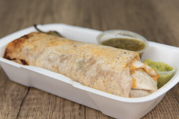 Loaded mexican cuisine burrito, bulging at the flour tortilla and served with a grilled jalapeno,...