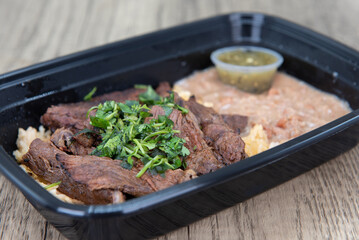 Take out order of ranchera with rice and beans is conveniently packed in a microwavable container