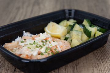 Overhead view of take out order of shrimp with Jasmin rice and chopped vegetables is conveniently packed in a microwavable container