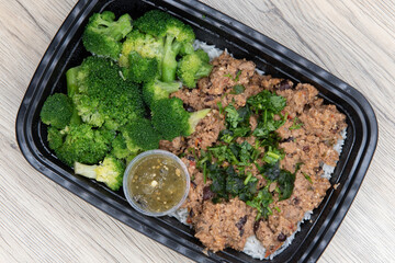 Overhead view of take out order of ground turkey with rice and broccoli is conveniently packed in a...