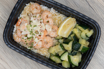 Take out order of shrimp with Jasmin rice and chopped vegetables is conveniently packed in a microwavable container
