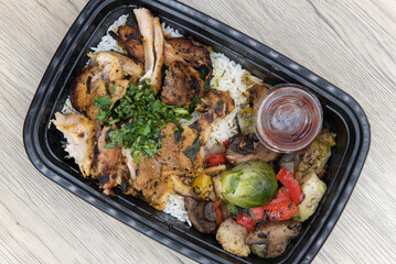 Overhead view of take out order of shawarma chicken with jasmin rice is conveniently packed in a microwavable container