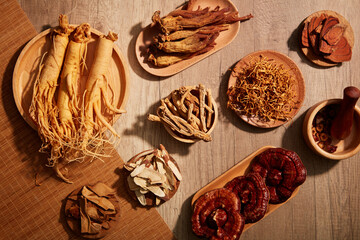 A wooden table with a platter of herbs including Ganoderma lucidum, cinnamon, ginseng, cordyceps,...
