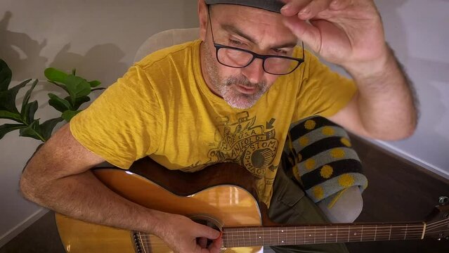 A weary older man on a small corner stage tunes a guitar and talks to the audience.