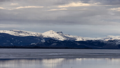 Fototapeta na wymiar View of a frozen Yellowstone Lake with snow covered mountains in American Landscape. Yellowstone National Park. United States. Nature Background.