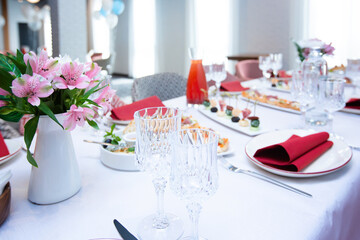 Beautiful table setting with dishes and flowers for a party, birthday, reception or other festive event. Glassware and cutlery for dinner.