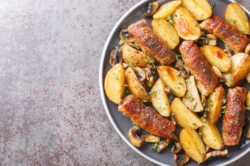 Baked beef rolls with potato wedges, mushrooms and thyme on plate closeup on the table. Horizontal top view from above