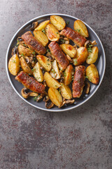 Roast beef rolls with baked potato wedges and mushrooms served on plate closeup on the table. Vertical top view from above