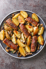 Baked pork rolls with mushrooms and potatoes close-up in a plate on the table. Vertical top view from above