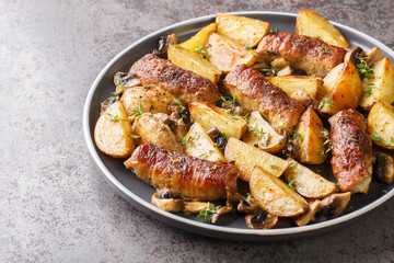 Tasty hot Baked Meat rolls with potato wedges, mushrooms and thyme on plate closeup on the table. Horizontal