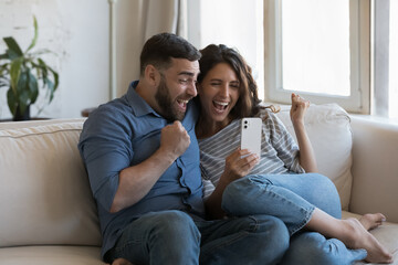 Couple read great news on phone scream with joy celebrate success, get fantastic commercial offer,...