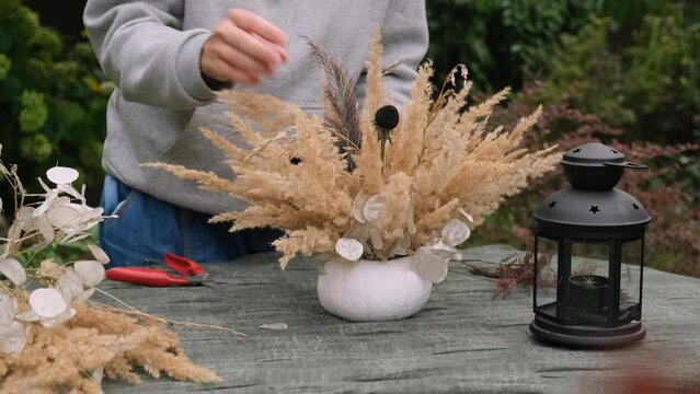 Florist makes autumnal DIY flower arrangement.