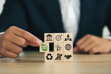 ESG concept of environmental, social, and governance. Sustainable corporation development.Businessman Hand holding Wooden blocks with ESG icons standing with other ESG icons.Net Zero.