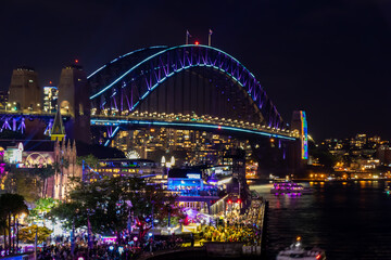 Obraz na płótnie Canvas 冬のシドニーのイベント・ビビッドシドニーで見た、青くライトアップされるハーバーブリッジと周辺の夜景