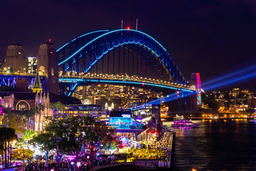 Obraz na płótnie Canvas 冬のシドニーのイベント・ビビッドシドニーで見た、青くライトアップされるハーバーブリッジと周辺の夜景