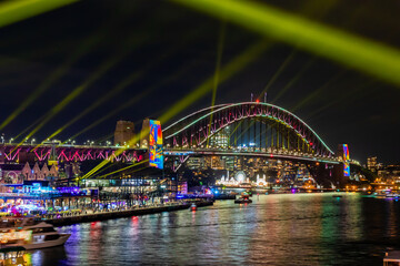 Fototapeta na wymiar 冬のシドニーのイベント・ビビッドシドニーで見た、紫にライトアップされるハーバーブリッジと周辺の夜景