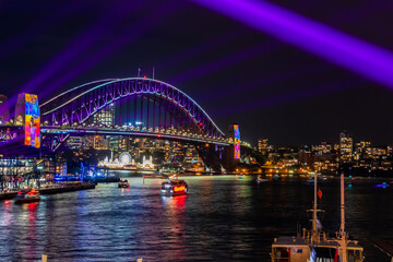 Naklejka na ściany i meble 冬のシドニーのイベント・ビビッドシドニーで見た、紫にライトアップされるハーバーブリッジと周辺の夜景