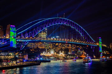 Fototapeta na wymiar 冬のシドニーのイベント・ビビッドシドニーで見た、青くライトアップされるハーバーブリッジと周辺の夜景