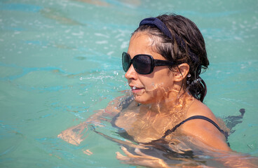 A girl with glasses swims in the pool.